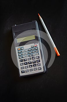 Vintage calculator and pencil. Finds in the attic of an old house. Antique things. Dark background. Vertical layout.