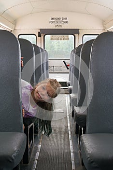 IThe young Caucasian blond girls is coming out from the bus`s seat. She is sitting in a school-bus.