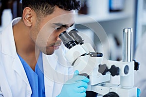 Itll be clearer once I magnify it. a young man using a microscope in a lab.