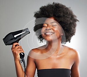 Itll be dry in no time. a young woman drying her hair against a grey background.