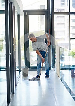 Itll shine like never before. a young man mopping the office floor.