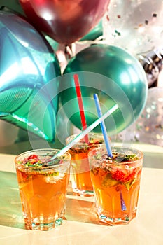 Ð¡itrus crushed ice cold refreshing cocktail with mint. Glass of strawberry soda drink on the background of balloons
