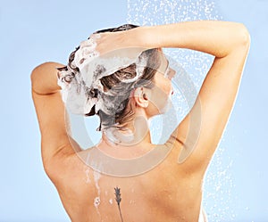 Its all clean. a young woman washing her hair in the shower against a blue background.