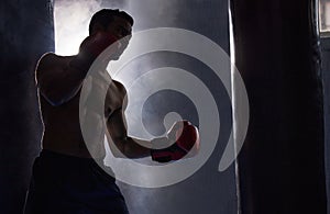 Its all about the combinations. a silhouetted young male boxer working out on a punching bag in the gym.