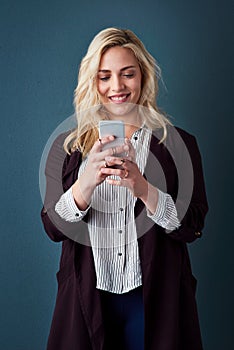 Its all about contacting the correct clients. Studio shot of a beautiful young businesswoman using a cellphone against a