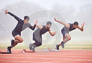 Its all about the start. Full length shot of three handsome young male athletes starting their race on a track.