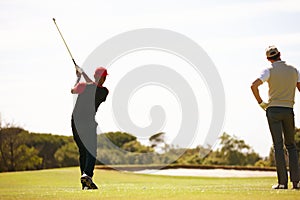 Its all in the swing. two handsome men playing a game of golf.