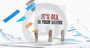 Its all in your hands text on paper sheet with chart, dice, spectacles, pen, laptop and blue and yellow push pin on wooden table