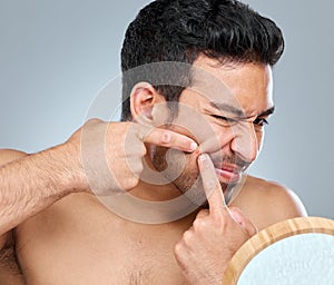 Its a bad habit but I cant stand pimples. a young man squeezing a pimple on his face.