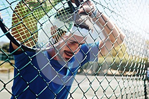 Its been a good training session. a handsome young sportsman taking a moment to breathe during tennis practise.