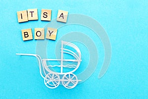 Its a boy. Little vintage white baby carriage stroller or pram on a blue background.