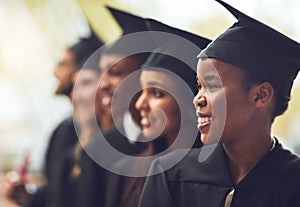 Its a bright future ahead of us. a group of fellow students standing in a row on graduation day.