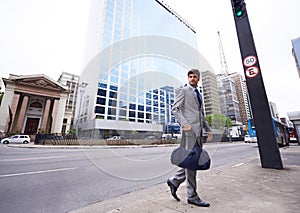 Its the city life for me. A full length shot of a handsome young businessman with a duffel bag walking in the city.