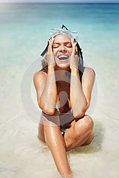 Its always fun in the sun. Cropped shot of an attractive young woman in scuba gear laughing while sitting on the beach.