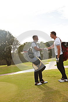 Its a gentlemans game. two young men shaking hands on a golf course.