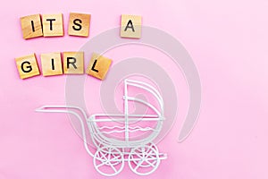 Its a girl. Little vintage white baby carriage stroller or pram on a pink background.