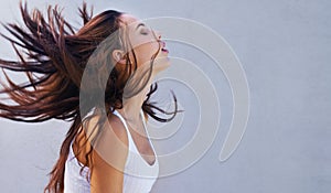 Its good to let your hair down. a beautiful young woman flinging her brunette hair.