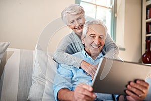 Its a great source of information. a senior couple using a digital tablet together in their living room at home.