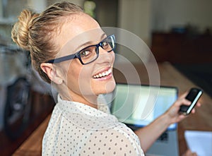 Its great to work from home. A young woman using her cellphone while working from home.