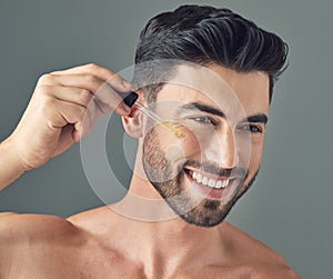 Its about having a health regimen not about looking pretty. a handsome young man applying serum to his face with a