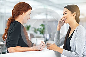 Its important to get along in the workplace. two businesswomen having a friendly conversation at the office.