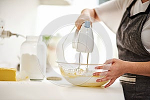 Its important to mix everything thoroughly. an unrecognizable woman using an electric mixer to mix her batter.