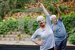 Its important to stay active in your old age. a senior couple doing yoga together outdoors.