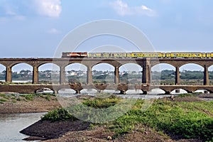 On its inaugural run, super-fast Duronto express train crossing an old stone arc bridge in Daund, Maharashtra, India photo