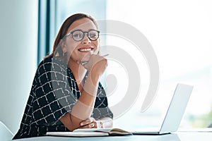 Its a lightbulb moment. Cropped portrait of a happy young businesswoman working on a laptop in an office.