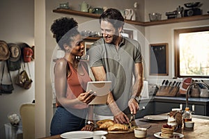 Its so much easier with all the recipes online. an affectionate young couple using a digital tablet while cooking