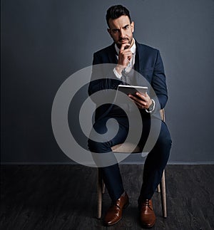 Its a must have app for the modern exec. Studio shot of a stylish young businessman using a digital tablet against a
