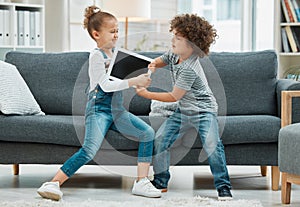 But its my turn. two siblings fighting in a game of tug of war over their digital tablet.