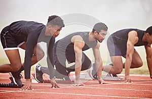 Its not just about pace. three handsome young male athletes starting their race on a track.