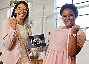 Its official. Were open. Cropped portrait of two attractive young female business owners holding an open sign while