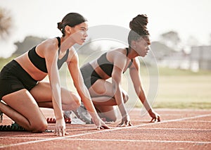 Its a one on one. Cropped shot of two attractive young female athletes starting their race on a track.