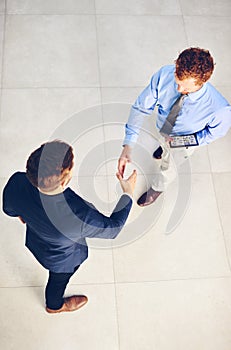 Its a pleasure to welcome you to our company. High angle shot of two businessmen shaking hands in an office.