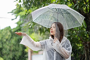 Its raining down hard. Shot of a young asian woman standing in the rain with an umbrella