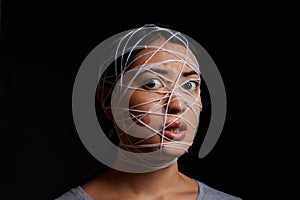 Its real to me. a young woman wrapped in string against a dark background.