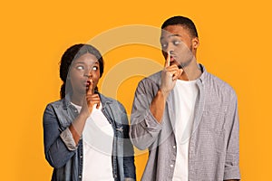 Its A Secret. Black couple making silence sign, keeping forefingers on lips