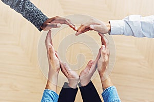 Its simple, love one another. High angle shot of a group of unidentifiable businesspeople forming a heart shape with