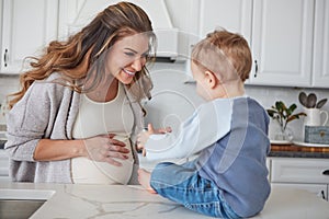 Its snack time. a pregnant woman and her son spending time together in the kitchen at home.