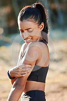 Its a struggle building muscle. a young woman experiencing muscle pain while working out in nature.