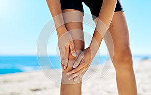 Its suppose to be hard, its what makes it great. a woman holding on to her injured knee while out for a run.