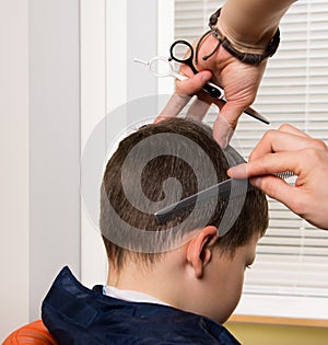 Its time for a new hairstyle. In the hands of a hairdresser there is a comb and scissors. haircut in a hairdressers child