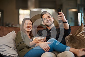 Its time for popcorn and binge watching. a young couple relaxing with popcorn on the sofa at home.