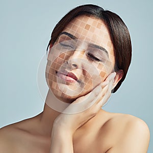 Its time to even that uneven skin tone. a young woman touching her face against a grey background. photo