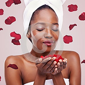 Its time to fall in love with you. Studio shot of a beautiful young woman in a towel surrounded by falling flower petals