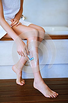 Its time to get smooth. a young woman shaving her legs in the bathroom.