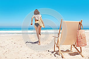 Its time to hit the water. Rearview shot of a sexy young woman walking towards the ocean with her surfboard.