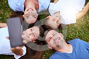 Its a weekend with the family. Portrait of a cheerful family lying on the ground while taking a self portrait together